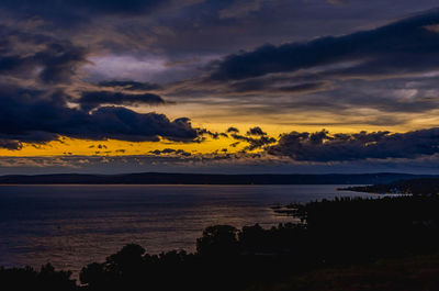 Scenic view of sea against dramatic sky during sunset