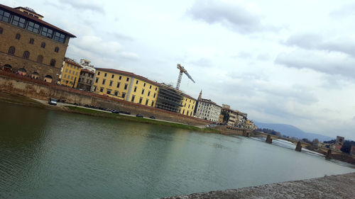 View of buildings by sea against cloudy sky