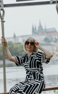 Blonde girl in sunglasses on a swing in a city park.