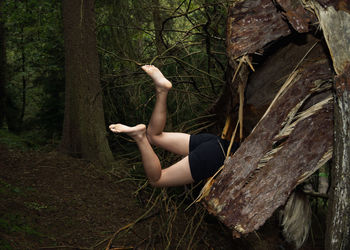 Woman on tree trunk in forest