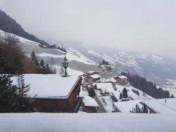 Houses on snow covered landscape against sky