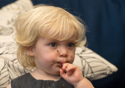 Close-up of toddler looking away with finger in mouth