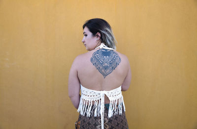 Woman looking away while standing against wall