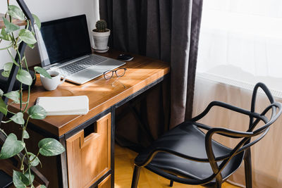 Modern workplace at home with laptop on wooden table at the room full of sunlight