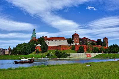 Buildings by river against sky