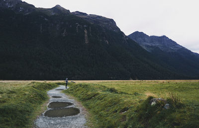 Person standing on footpath against mountain