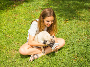 Portrait of teenage girl with dog on field