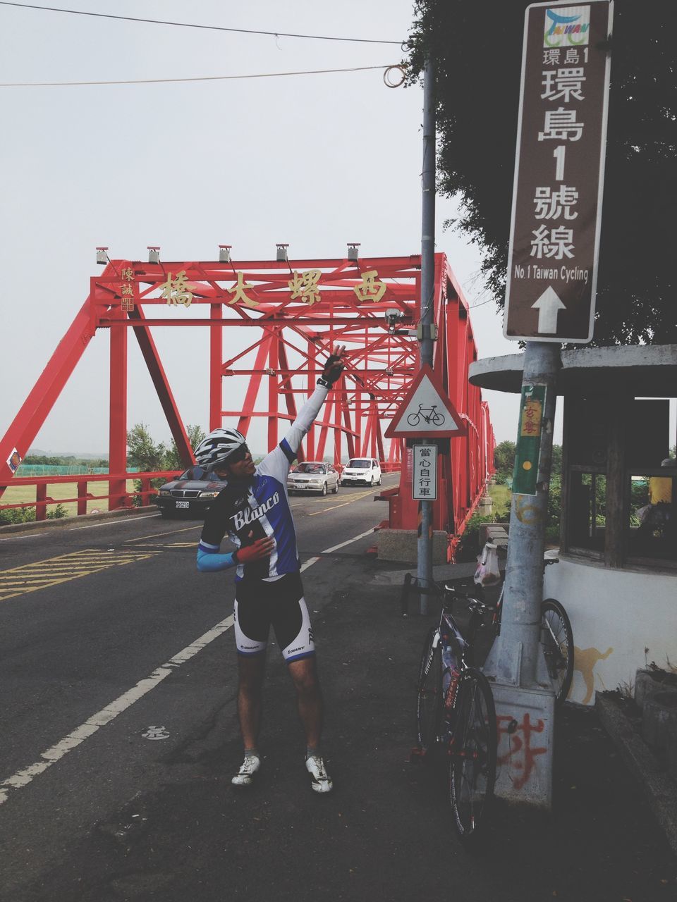 transportation, men, clear sky, mode of transport, land vehicle, street, lifestyles, bicycle, text, communication, built structure, road, leisure activity, western script, architecture, walking, full length, outdoors