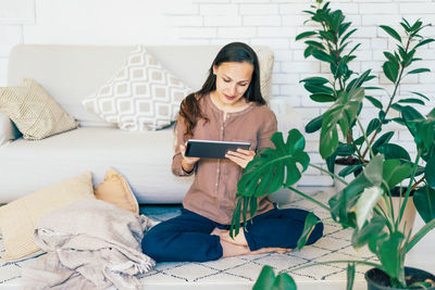 Young woman using mobile phone while sitting on bed