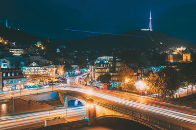 High angle view of light trails on street amidst buildings at night