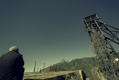 Rear view of man standing on landscape against clear sky