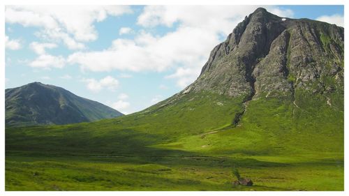 Scenic view of green landscape and mountains against sky