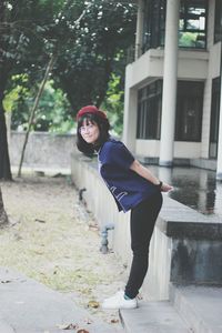 Portrait of young woman standing against trees