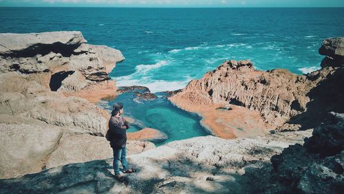 Full length of man standing on rock at beach