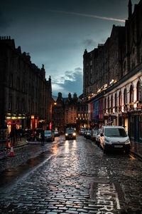 City street amidst buildings against sky during rainy season