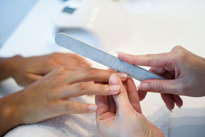 Close-up of beautician cutting woman nail