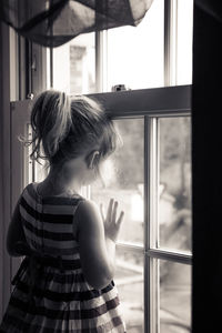 Girl looking through window at home