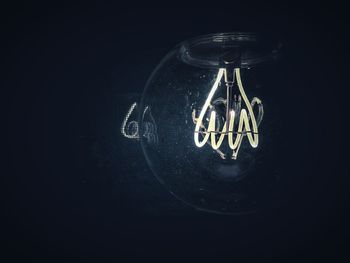 Close-up of illuminated light bulb against black background