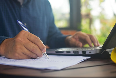 Midsection of man using mobile phone on table