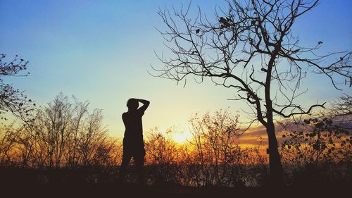 Silhouette man standing on field against sky during sunset