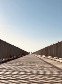 Man on railing against clear blue sky