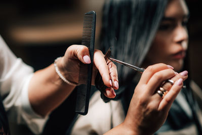 Cropped hands of hairdresser cutting woman hair in salon