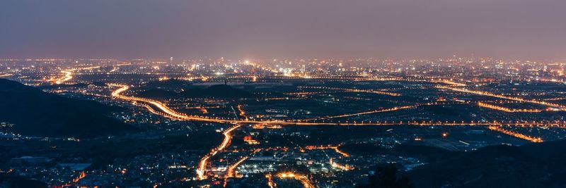 High angle view of illuminated cityscape against sky at night