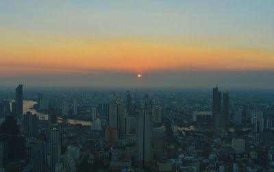 Aerial view of buildings in city at sunset