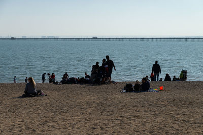 People at beach against clear sky