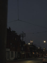 Illuminated street by buildings in city at night