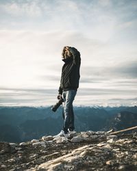 Full length of woman standing on rock against sky