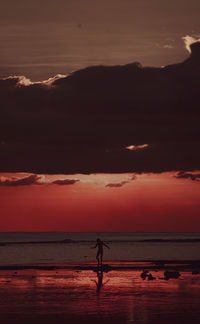 Silhouette person standing on beach against sky during sunset