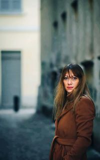 Portrait of young woman standing against building