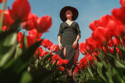 Woman standing by red flowering plants