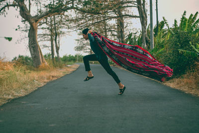 Side view of man running on road amidst trees