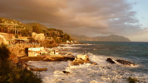 Mountain by sea against cloudy sky