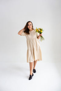 Portrait of young woman standing against white background