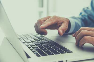 Closeup man hands typing on computer keyboard. businessman using laptop at home. office workplace