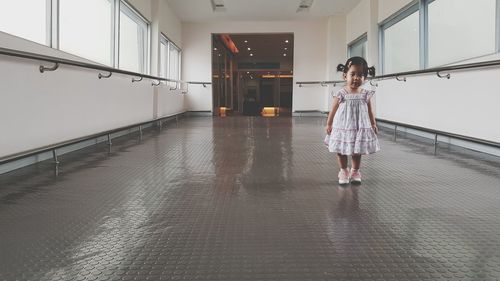 Portrait of cute girl standing at hallway in building