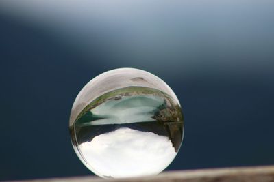 Close-up of crystal ball against sky