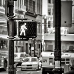 Pedestrian crossing sign against vehicles on street in city