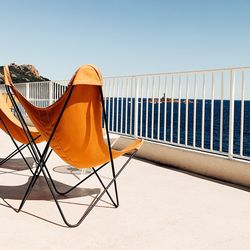 Empty chair on beach against clear sky