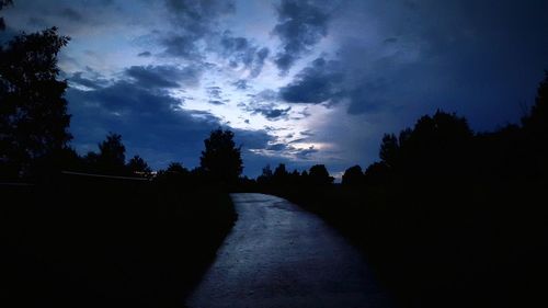 Silhouette trees on road against sky
