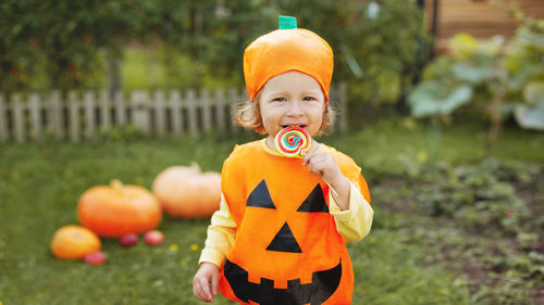 Portrait of smiling girl eating lollipop standing at park