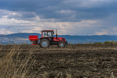 Tractor spreading artificial fertilizers at summer