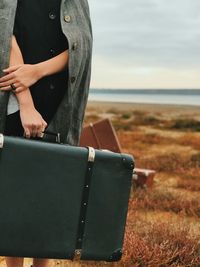Midsection of man using laptop while sitting on field