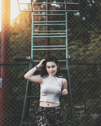 Portrait of smiling woman standing by fence