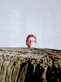 Teenage boy with eyes closed standing by wood against wall