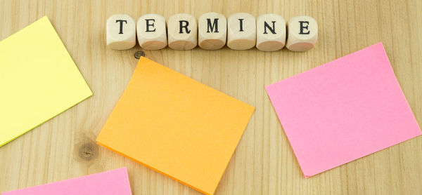 Directly above shot of wooden letter blocks with adhesive notes on table