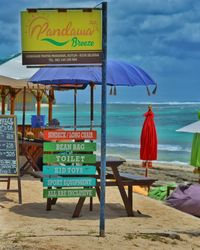 Information sign on beach against sky